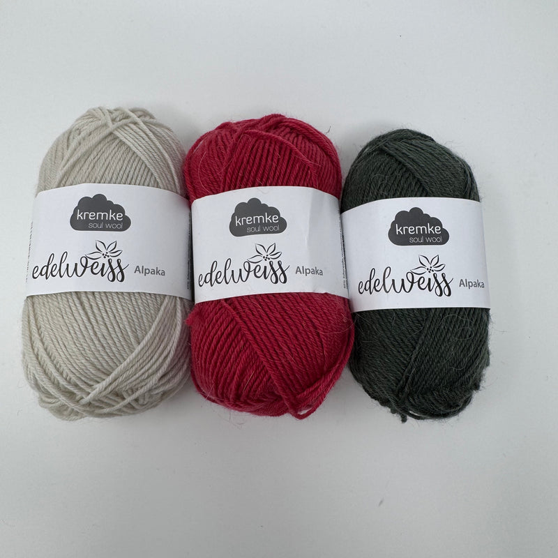 Three balls of Edelweiss Alpaka 4 ply in vintage cream, red and dark green